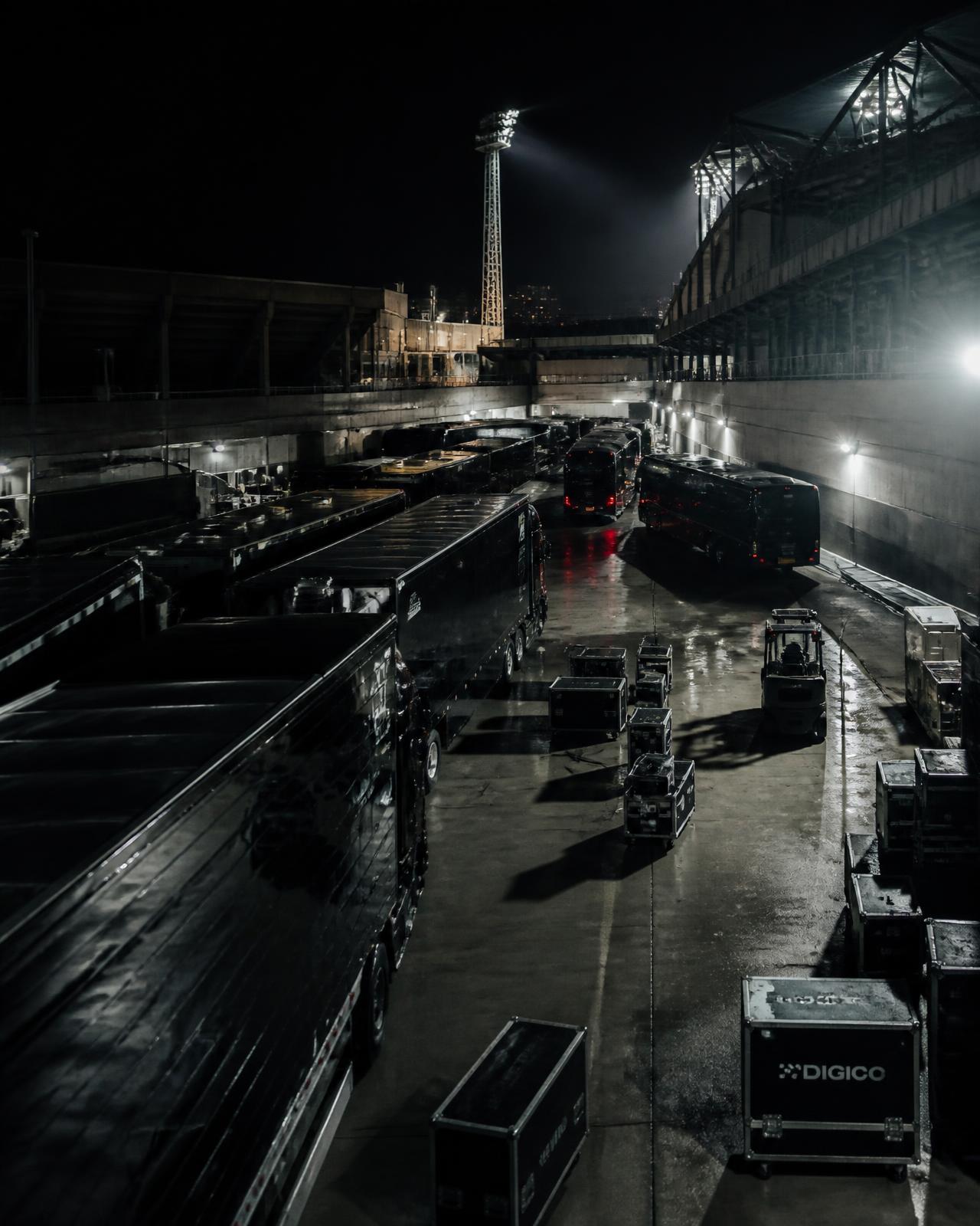 Touring coaches and equipment trucks at a venue loading area